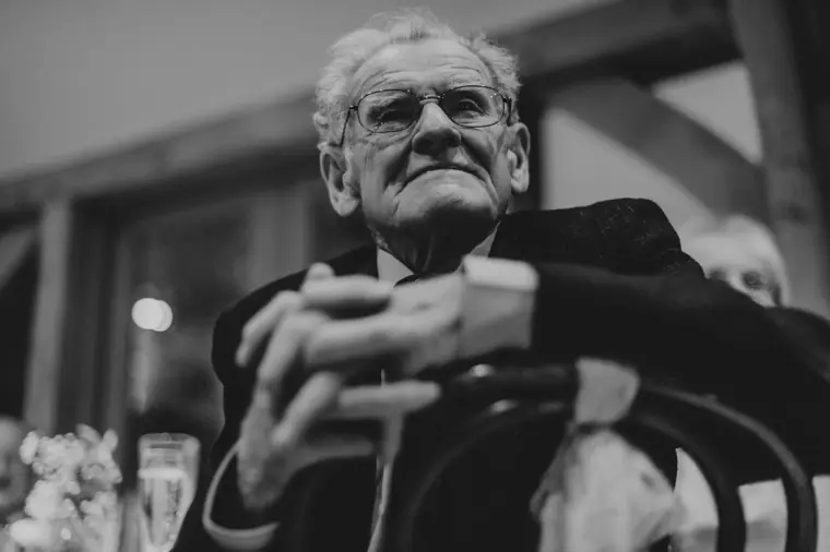 Black-and-white portrait of an older guest listening to the speeches