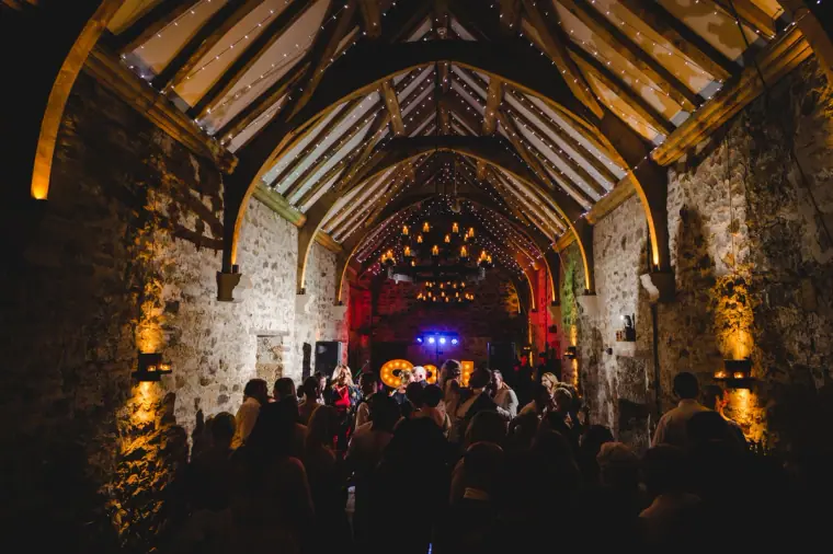 Guests crowding the dance floor beneath the beamed ceiling