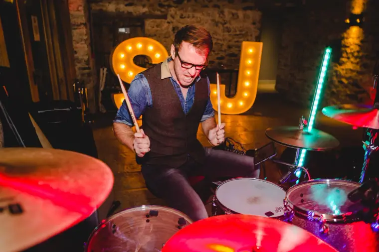 Drummer playing in front of the glowing S&J marquee letters