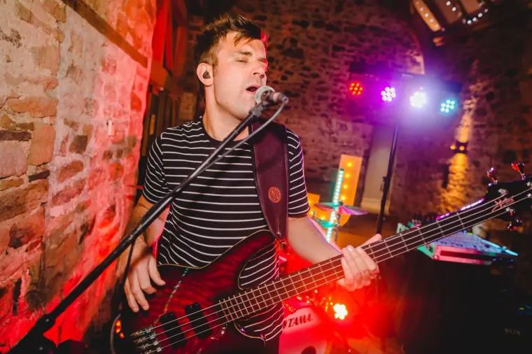 Bass player in a striped top singing with the band