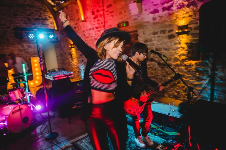 Singer in red trousers performing with the band under coloured lights