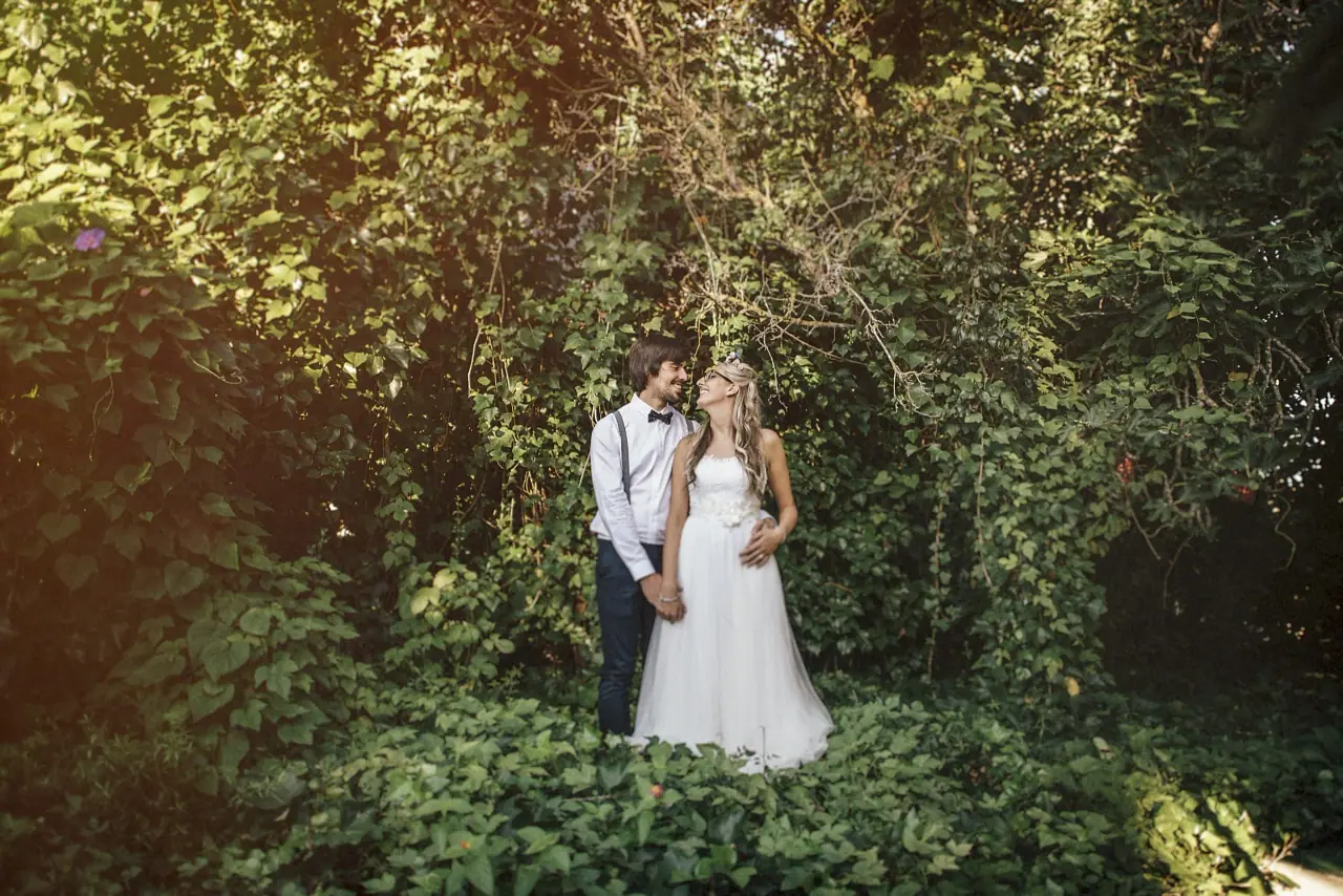 Bride and groom in braces standing together in lush green woodland at Hidden Bar, Ibiza