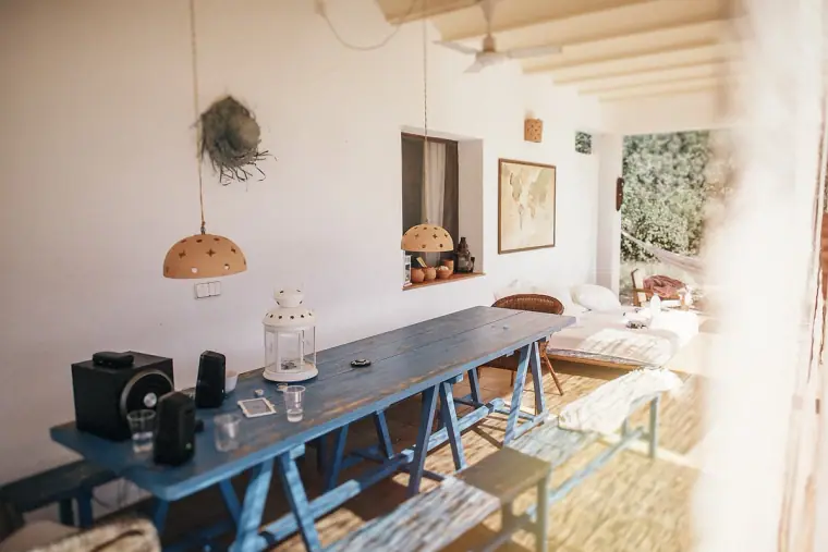 Bright villa room with a long blue table and benches beside open doors