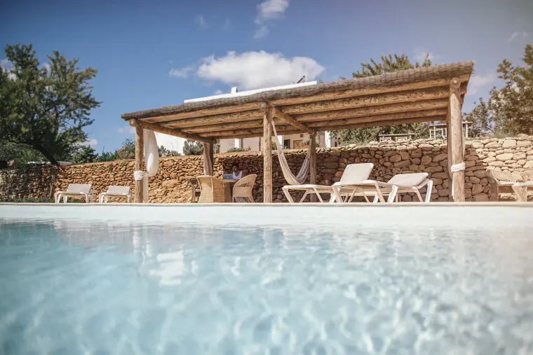 Sparkling pool beside a wooden pergola with sun loungers