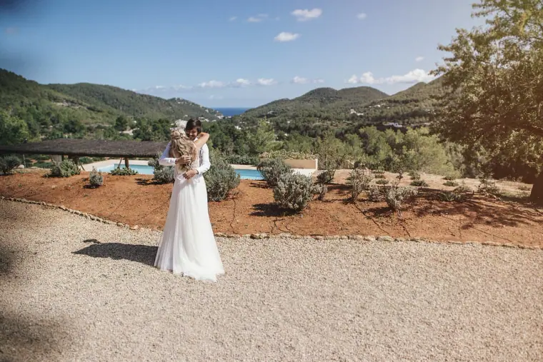 Bride walking across the gravel terrace towards the waiting groom