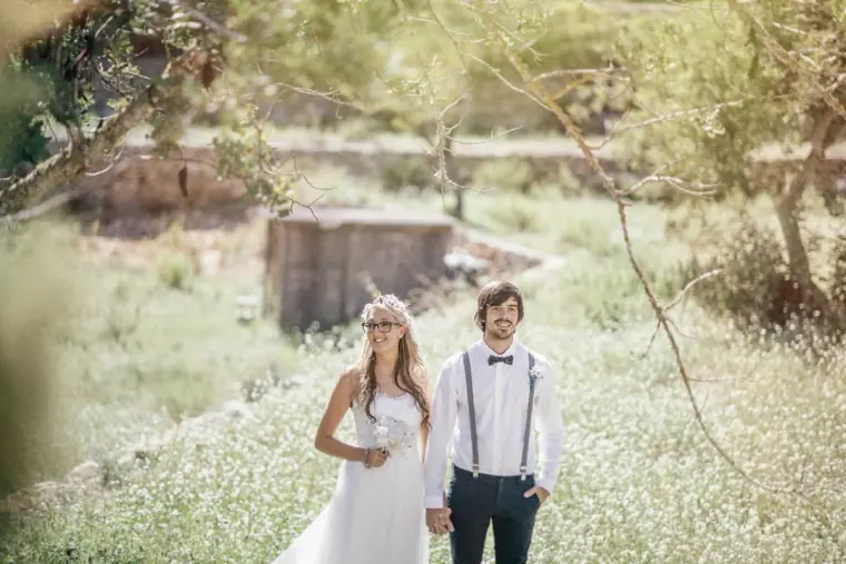Bride and groom walking through a meadow of white wildflowers