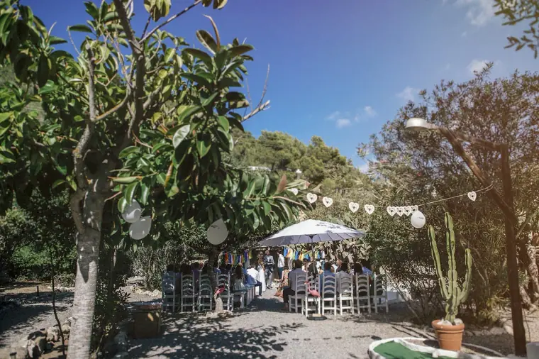 Wide view of the outdoor ceremony under trees and string lights