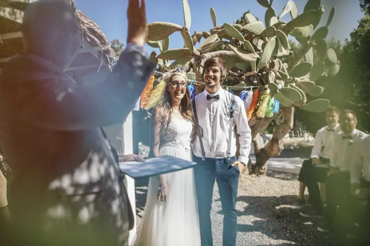 Newlyweds smiling together beneath a cactus and tassel garlands