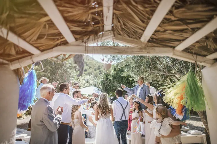 Guests mingling with the couple beneath the thatched pergola after the ceremony