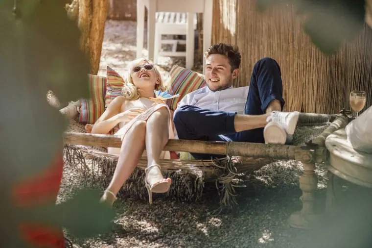 Bride and groom relaxing on a rustic daybed in the garden