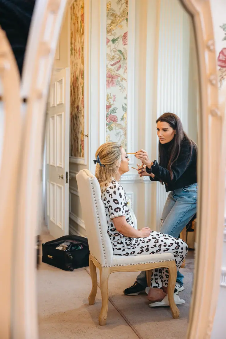 Bride having her make-up done, reflected in an ornate mirror