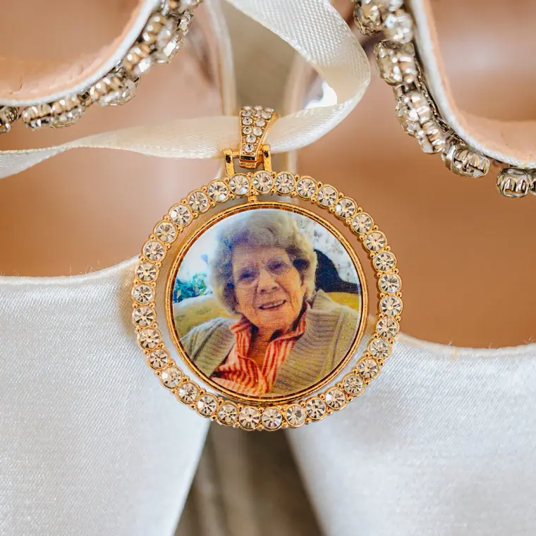 Gold photo locket of a loved one hanging between diamanté shoe straps