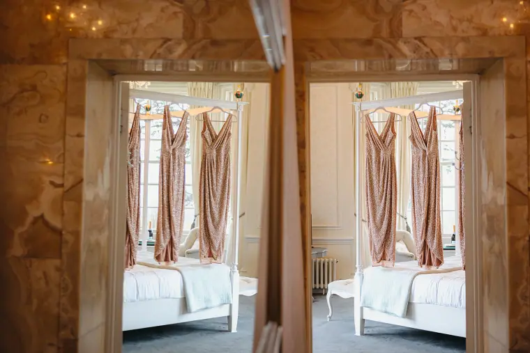Blush bridesmaid dresses hanging in two doorways, mirrored side by side