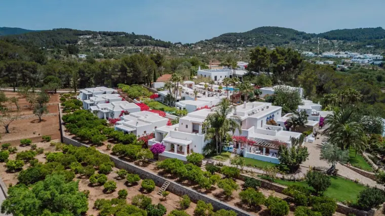 Aerial view of Can Curreu's whitewashed villas among gardens and orchards in the Ibiza hills
