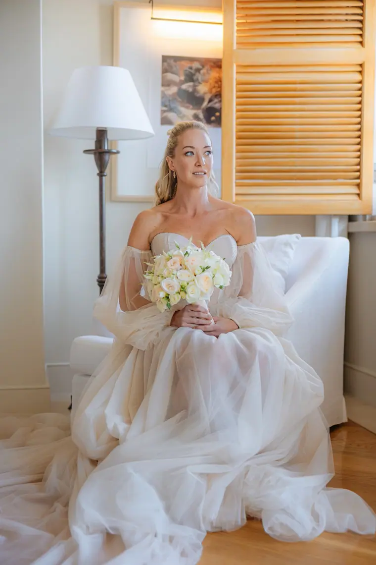 Jade seated in a tulle gown with puff sleeves, holding white roses