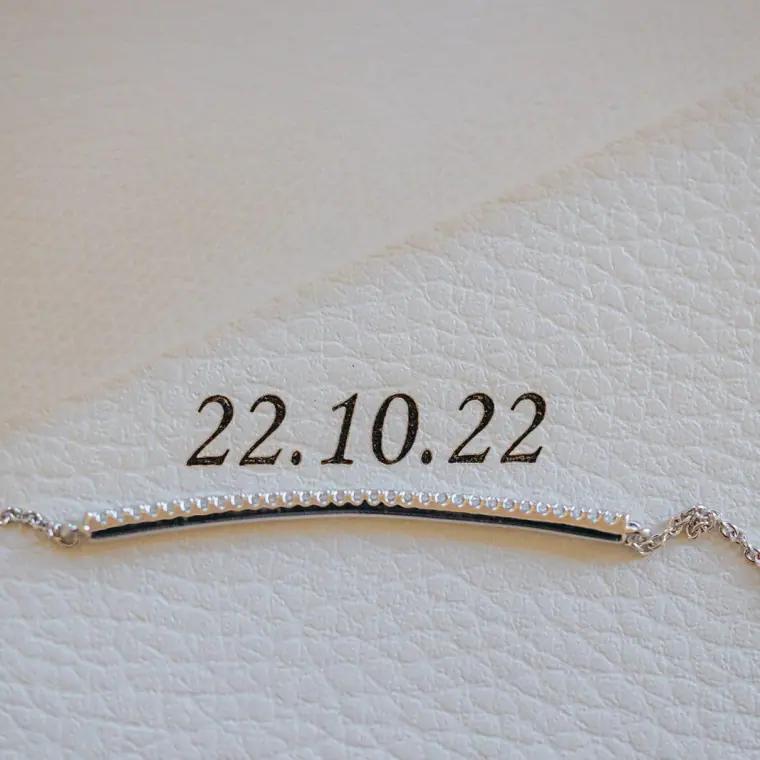 Delicate bracelet on white leather embossed with the date 22.10.22