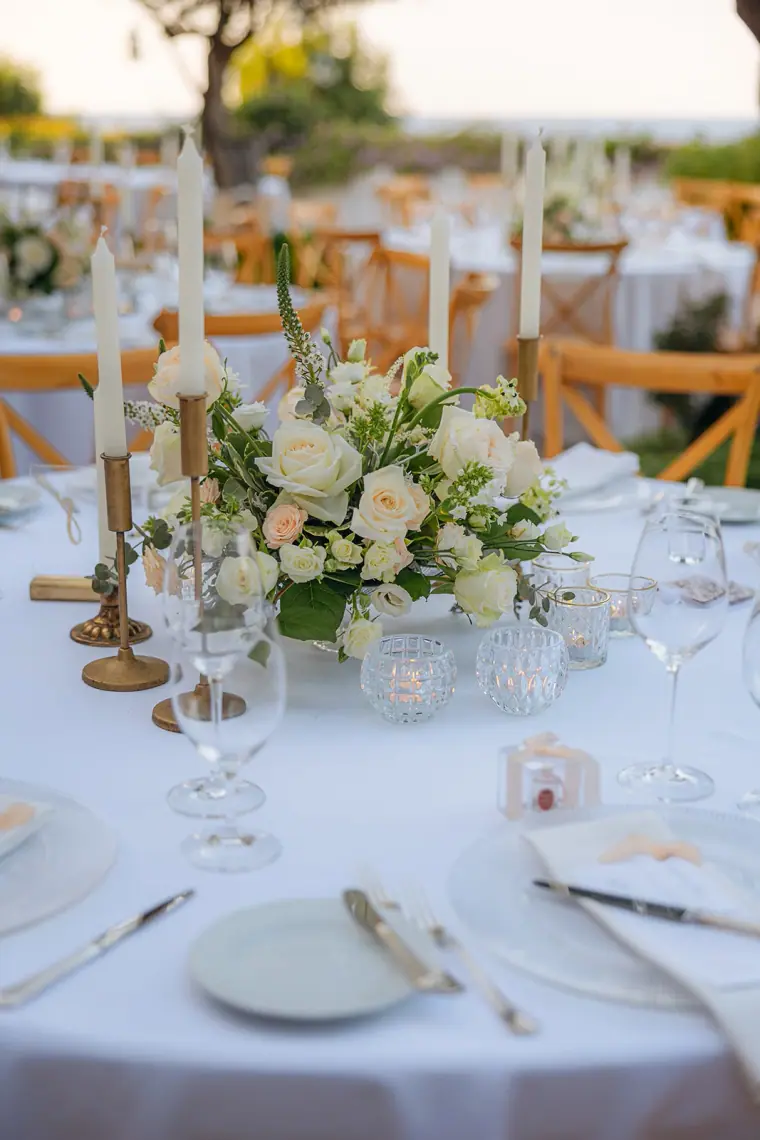 Round reception table with white flowers, gold candlesticks and glassware
