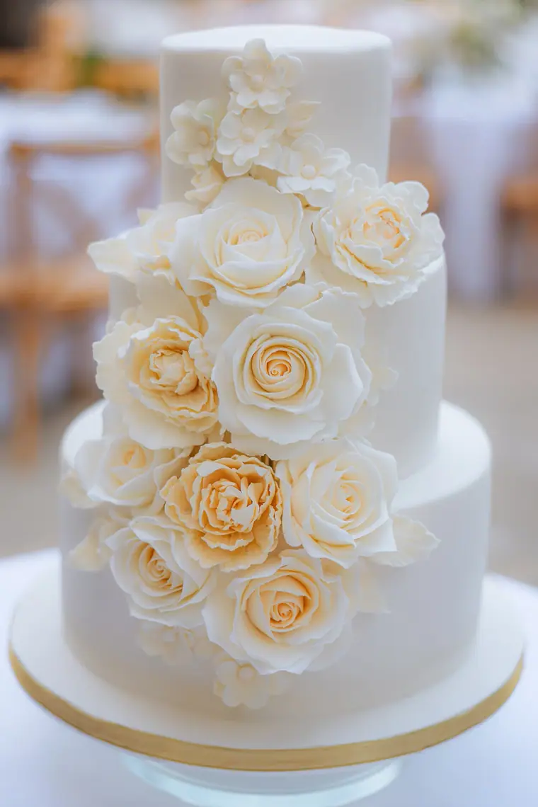 Three-tier white cake cascading with ivory sugar roses