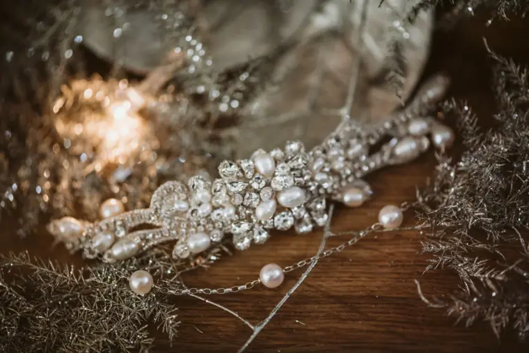 Pearl and crystal bridal hair vine resting on wood among silver foliage