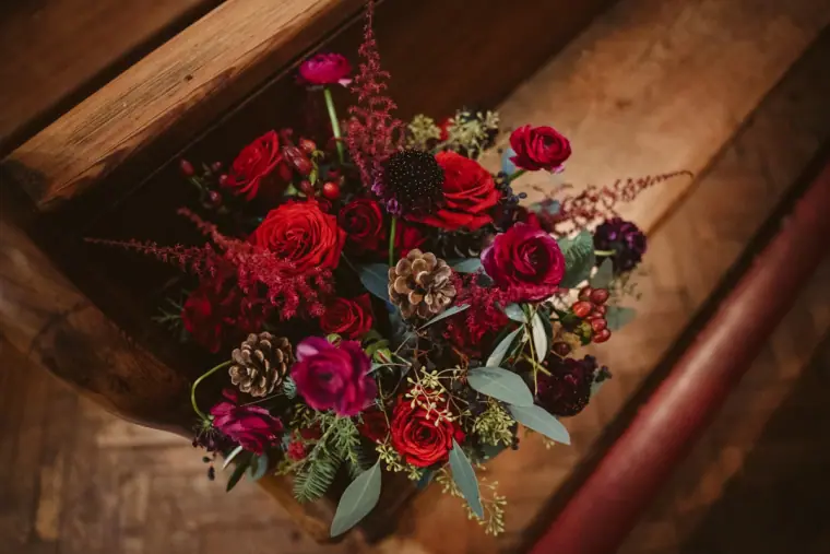 Red roses, ranunculus and pine cones in the bride's winter bouquet