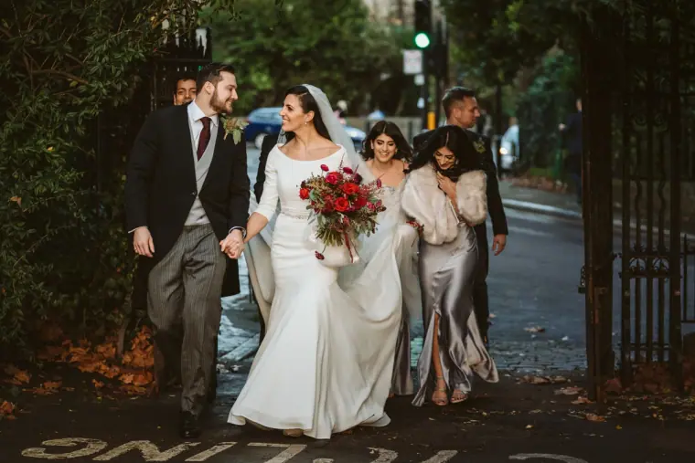 Newlyweds walking down the street with the bridal party after the church ceremony
