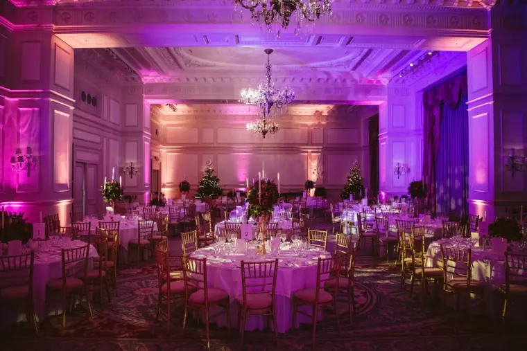 Ballroom at The Landmark London lit in purple and pink, round tables set for dinner