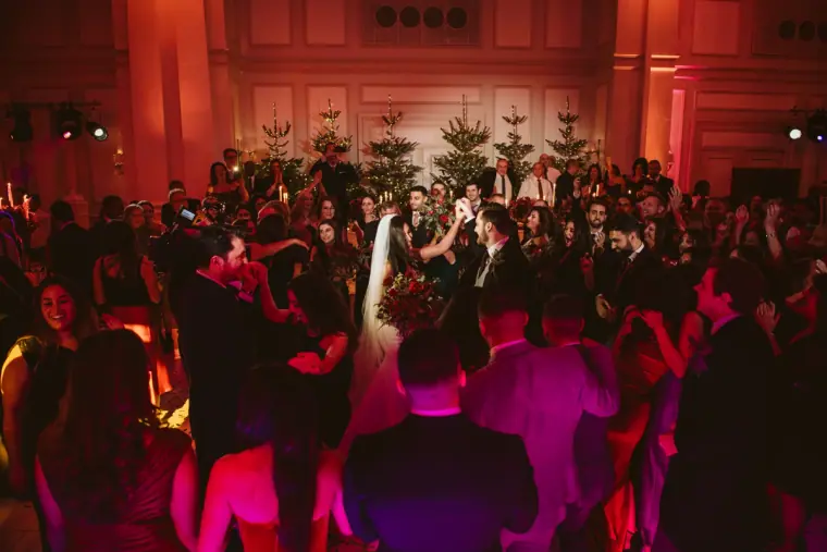 Crowded dance floor of guests under red light in the ballroom