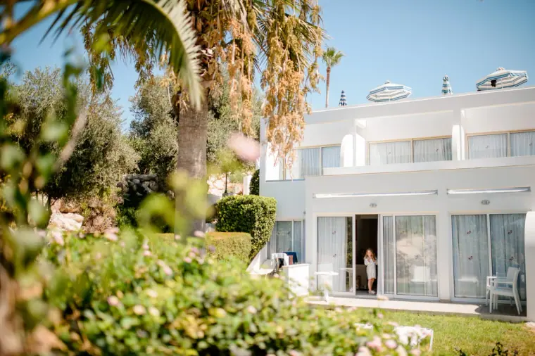 White hotel building framed by palms and gardens at Laura Beach Hotel, Paphos