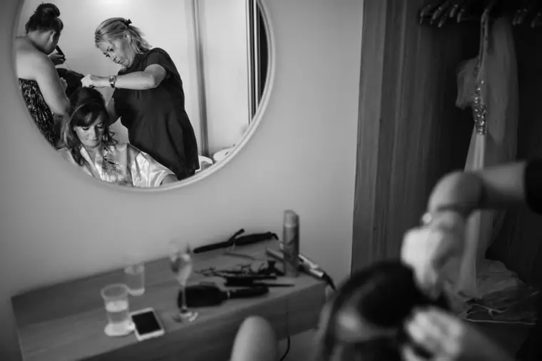 Black-and-white photo of bridal hair styling reflected in a round mirror