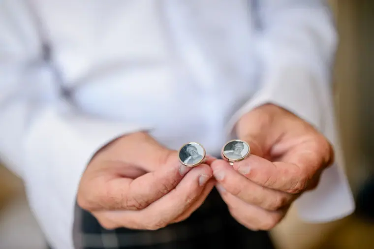 Close-up of hands fastening silver cufflinks on a white shirt