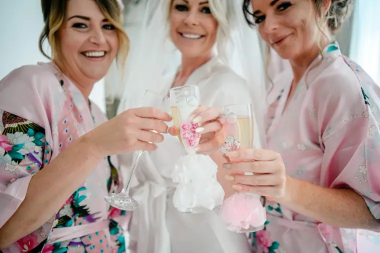 Bride and bridesmaids in floral robes raising glasses of fizz