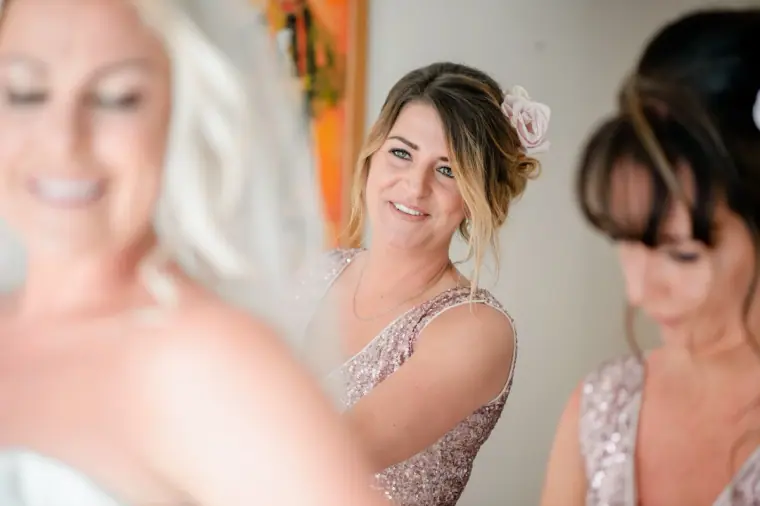 Bridesmaid in a sequinned blush dress smiling at the bride