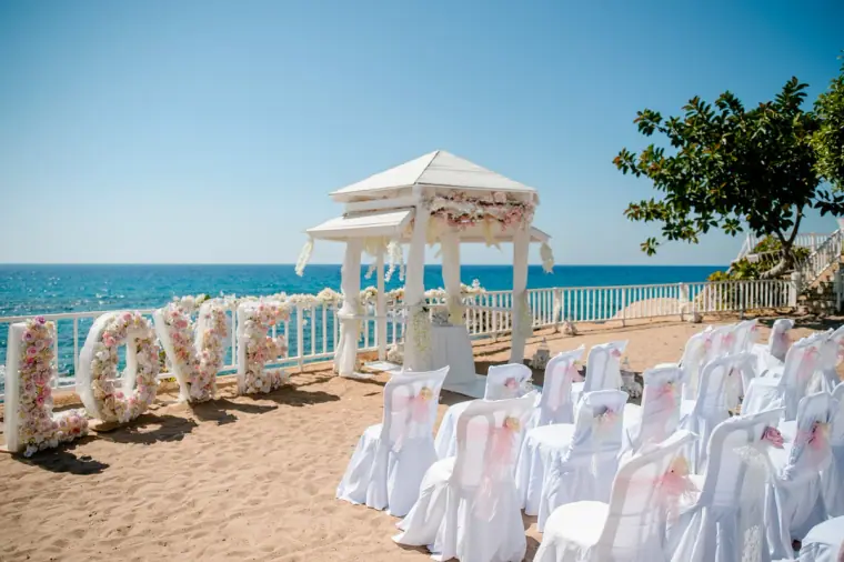 Gazebo, white chairs and a floral LOVE sign set up by the sea at Laura Beach Hotel, Paphos