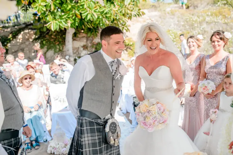 Groom grinning at the bride as guests look on during the ceremony