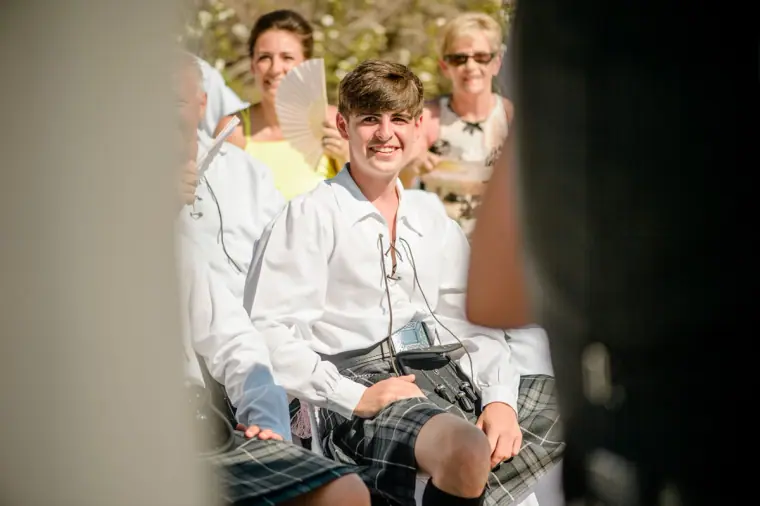 Young guest in a kilt grinning in the front row during the ceremony