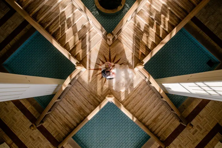 Couple seen from far below through a cross-shaped wooden atrium roof
