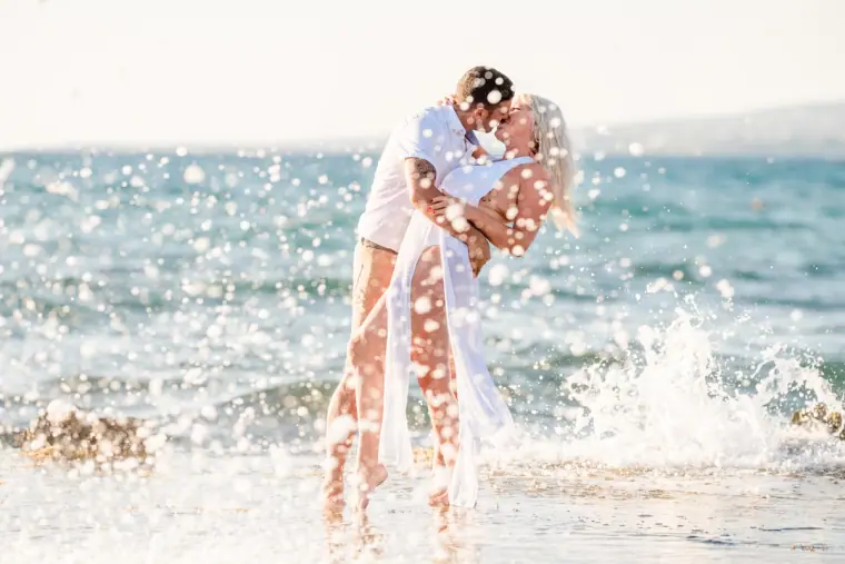 Couple kissing as he dips her in sparkling shallow sea water