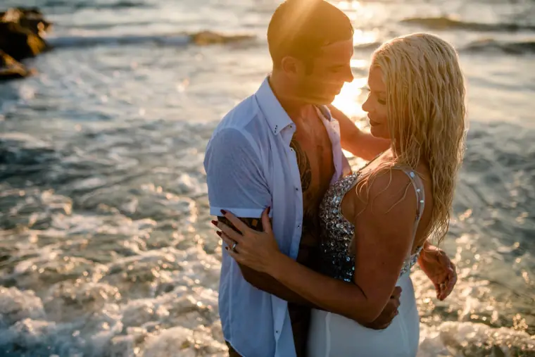Couple embracing in the surf, the bride in a sparkly wedding dress