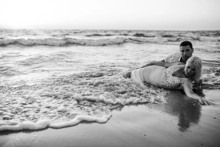 Black-and-white photo of the couple lying in the surf on the beach