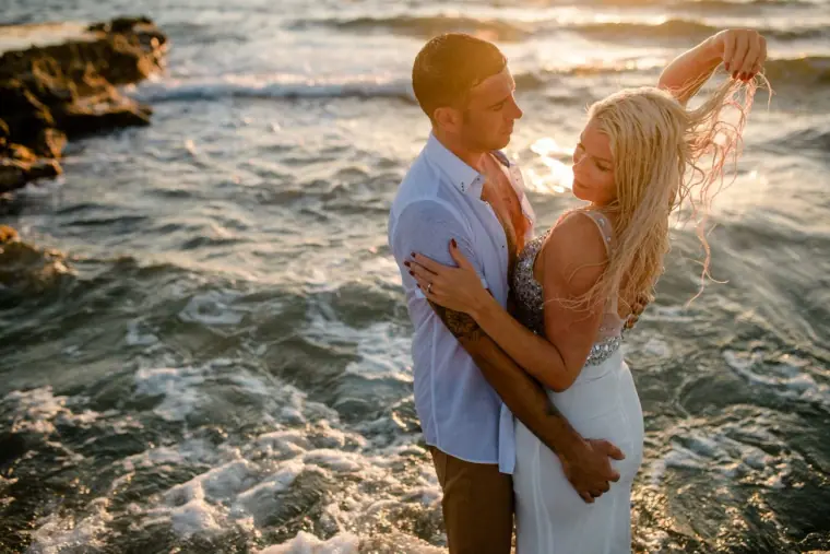 Maryellen and Ben embracing among the waves at sunset, Paphos