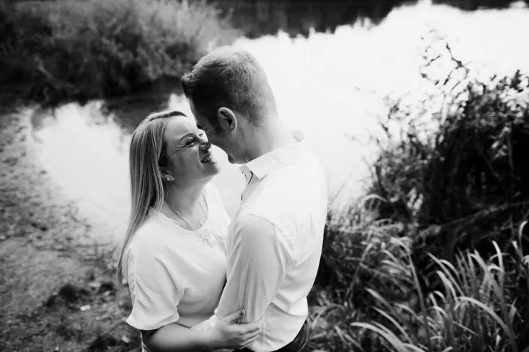 Black-and-white photo of Lauren and Anthony nose to nose beside the lake at Virginia Water