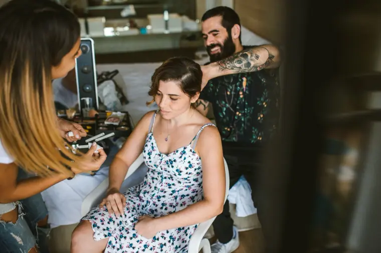 Bride smiling as makeup artist and hairdresser work on her together
