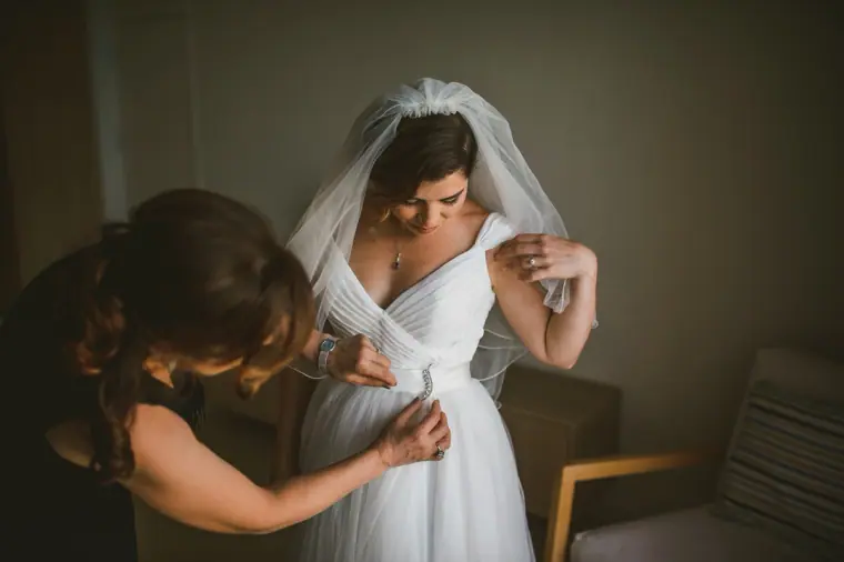 Bride's mother fastening the back of her wedding dress