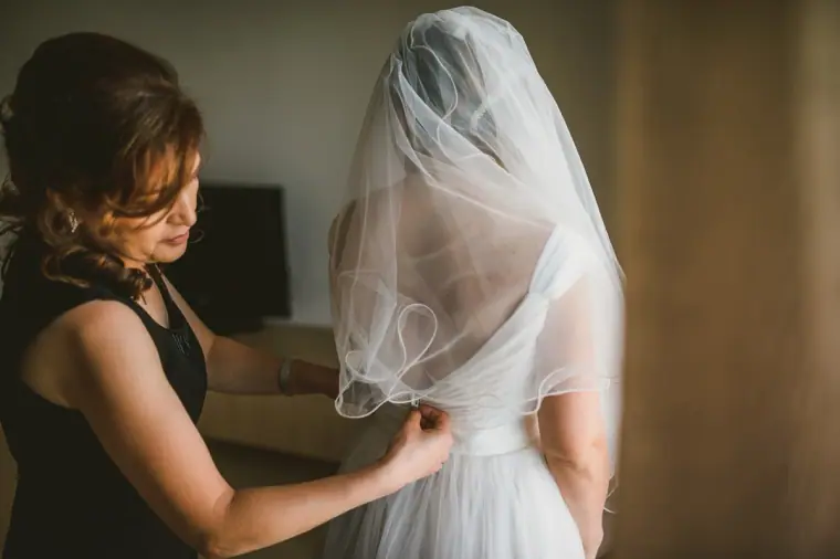 Bride's mother adjusting the veil over the back of the bride's dress