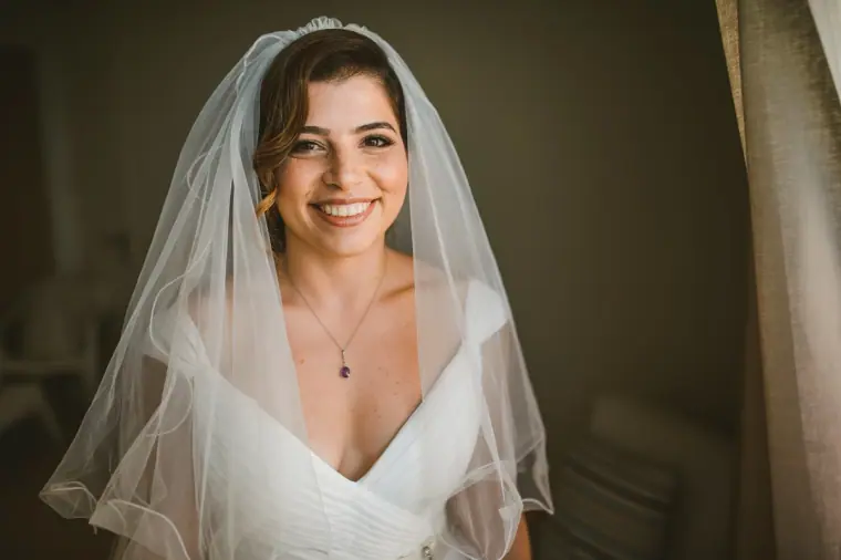 Close portrait of the smiling bride in her fingertip veil and pendant necklace