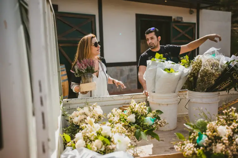 Florists unpacking buckets of white flowers outside a stable building