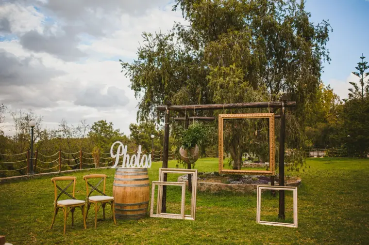 Photo corner with empty frames, wooden chairs and a barrel on the lawn