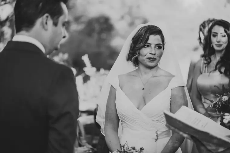 Black-and-white photo of the bride smiling at the groom during the ceremony