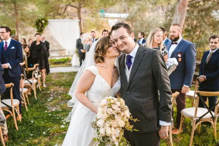 Nermine and Christopher cheek to cheek walking down the aisle among guests