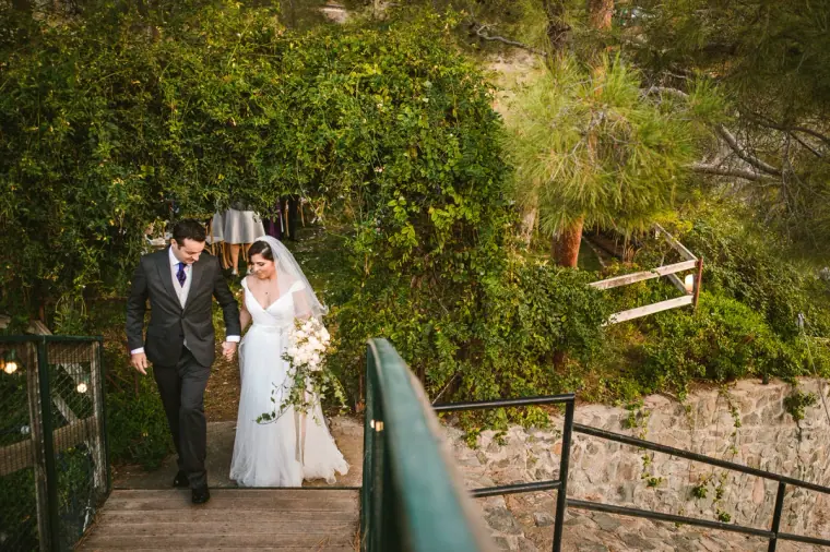 Bride and groom walking down wooden steps through green foliage after the ceremony